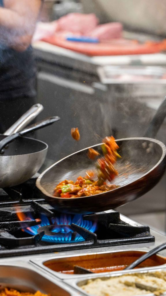 Cuisinier d'O'Grill faisant sauter de la viande et des poivrons à la poêle sur la flamme, cuisine du restaurant turc halal près de Dijon