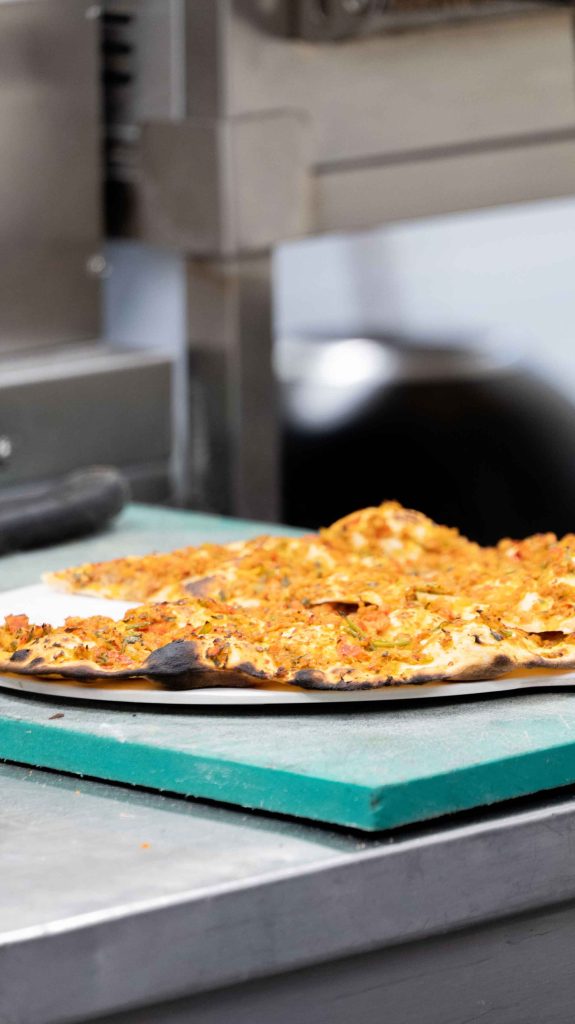 Lahmacun turc à la pâte fine garni de viande hachée halal, tout juste sorti du four dans la cuisine d'O'Grill près de Dijon