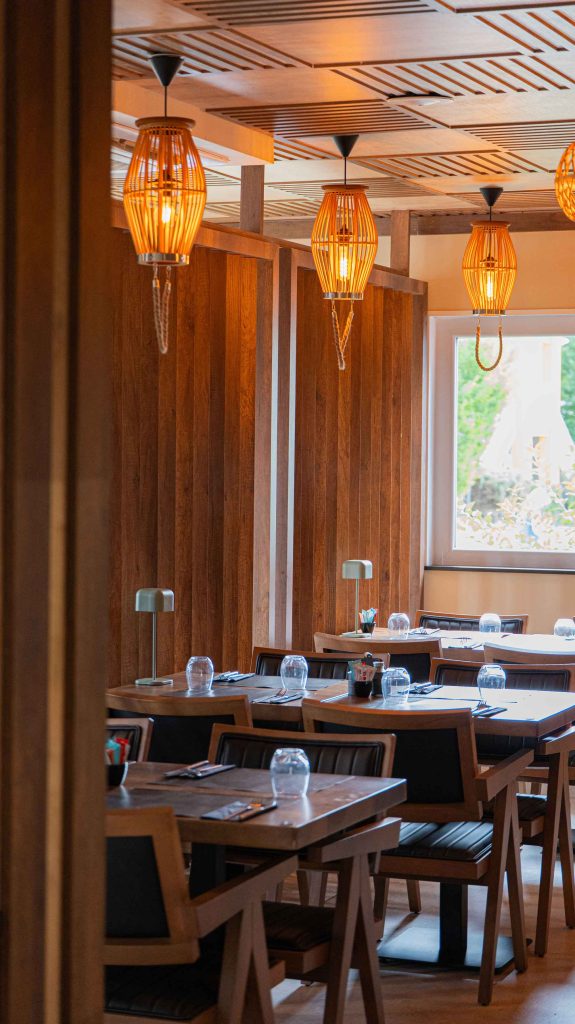 Salle chaleureuse du restaurant turc halal O'Grill près de Dijon, avec cloisons en bois, suspensions en rotin et tables dressées